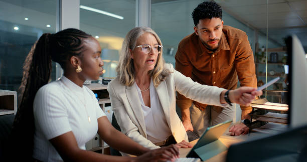 istock Business, employees and computer with training in office to prepare accounting reports or filing system process. Mentor, mature manager or helping interns to track financial payments or budget review 2187408442