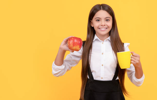 happy school kid in uniform hold apple and water bottle, water hydration.