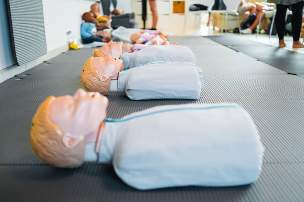 CPR training session featuring life-sized mannequins on mats, used for realistic first aid and emergency response practice in a classroom setting.