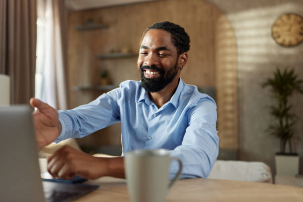 istock Happy black man having a video call over laptop at home. 2187421603