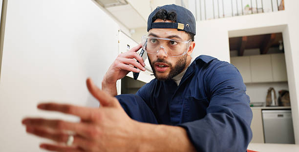 istock Plumber, worker and man with phone call in kitchen for pipeline problem, leakage repair and sink maintenance. Plumbing contractor, handyman and contact owner for filter system installation in home 2187421667
