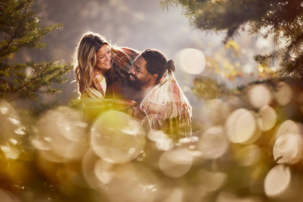 Happy diverse couple having fun while piggybacking during autumn day in nature.