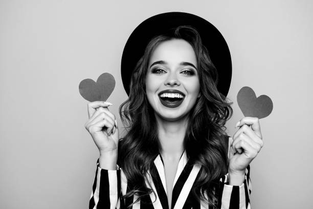 istock Charming pretty nice, comic, funny, modern, cheerful, laughing girl in black and white jacket having two small paper heart in hands, isolated on pink background 2187423818