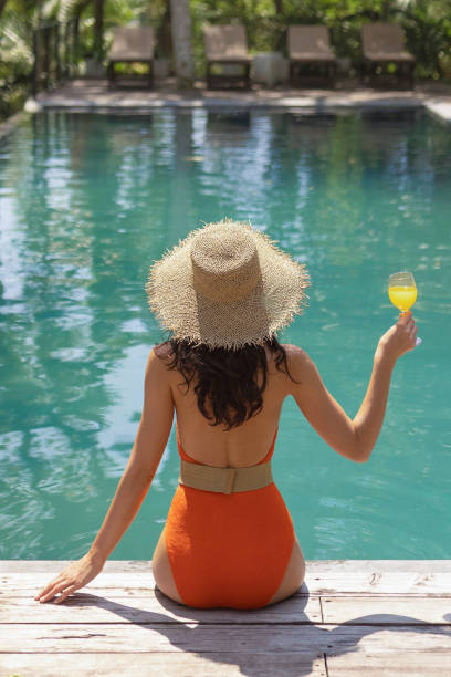 istock Woman in Orange Bikini Relaxing by Pool with Drink 2187426135