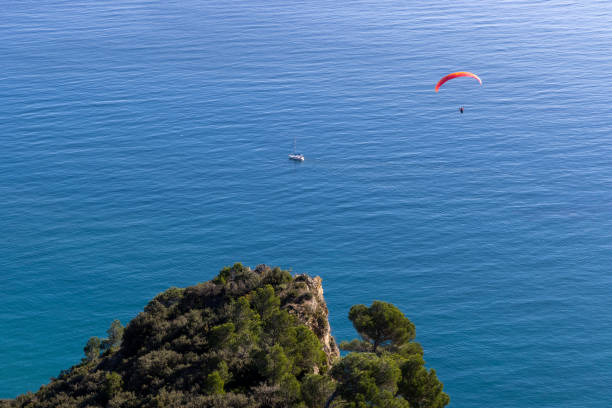 Elevated view of paraglider sailing over Mediterranean coastline