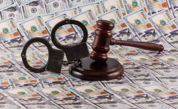 istock Handcuffs and a judge's gavel against a background of $100 bills 2187432425