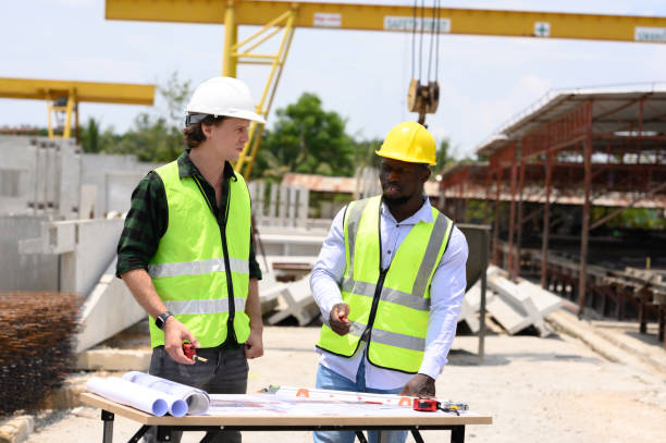 istock Engineers and foremen wearing hard hats in factory. Hard hats talking on construction site. 2187438570