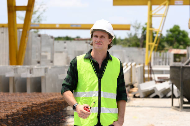istock Young engineer wearing a hard hat in a factory inspecting work at a construction site. 2187438647