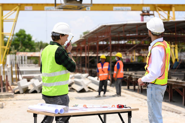 istock Engineers and foremen wearing hard hats in factory. Hard hats talking on construction site. 2187438651