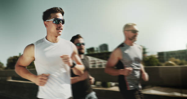 istock Men, runner and group for exercise in city on bridge for training, challenge and motion blur in summer with speed. People, friends and fitness in urban street, fast and workout in morning 2187438909