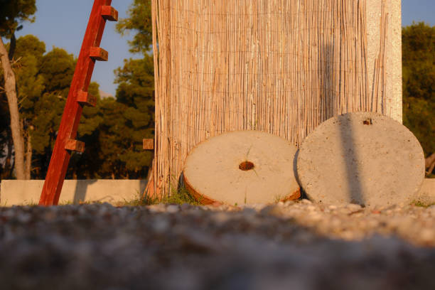 Two stone circles lie near the stone wall. A bamboo curtain hangs on the wall. To the left is a red staircase