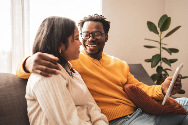 Happy couple enjoying digital tablet together on the couch
