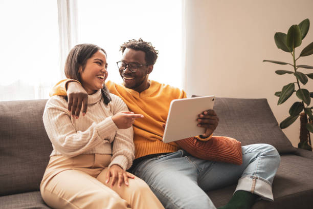 istock Happy couple enjoying digital tablet at home on cozy sofa 2187441941