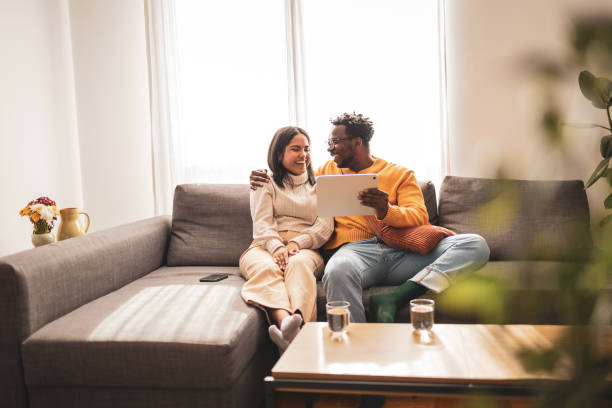 istock Happy couple relaxing on a couch using a digital tablet 2187441947
