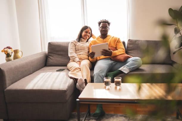 istock Couple relaxing on a sofa browsing digital tablet at home 2187441949