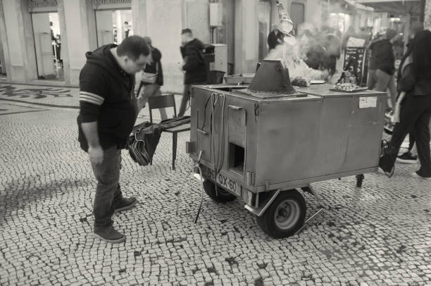 Lisbon, Portugal - November 1, 2023: A traditional roasted chestnuts seller waits for clients at the Rua Augusta street in Lisbon downtown.