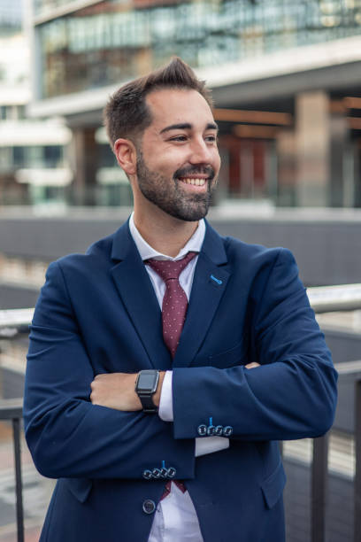 istock Smiling businessman looking away with folded arms in urban setting 2187447893