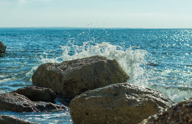Photo of sea waves crashing against rocks on a Cyprus beach, with water splashes, capturing the power and beauty of the ocean tide