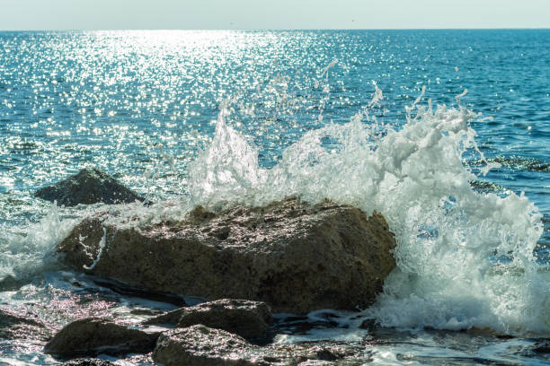 Photo of sea waves crashing against rocks on a Cyprus beach, with water splashes, capturing the power and beauty of the ocean tide