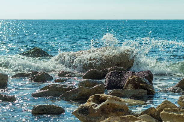 Photo of sea waves crashing against rocks on a Cyprus beach, with water splashes, capturing the power and beauty of the ocean tide