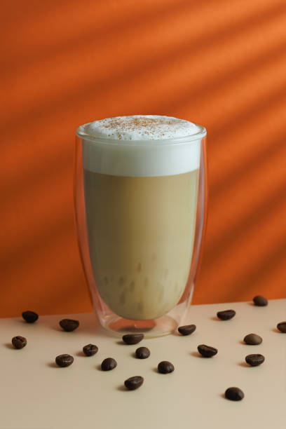 istock cappuccino in double glass and coffee beans on table on the orange background 2187458388