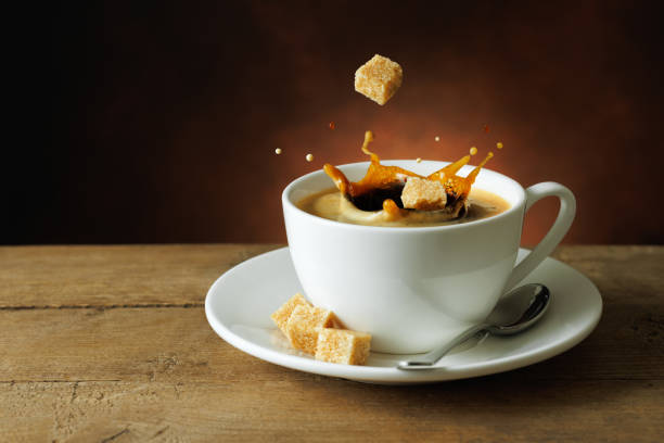 istock cane sugar cubes falling into cup of coffee with splashes on table 2187458408