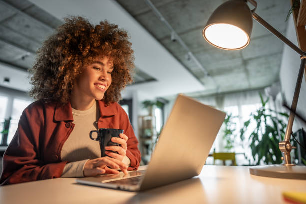 istock Online learning. Young female student with curly hair is using a laptop in her home. 2187460444