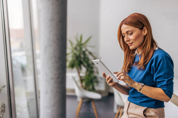 A smiling businesswoman is using a digital tablet in the office