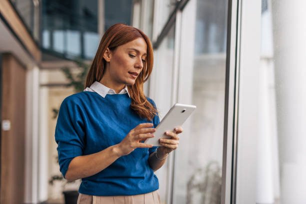 istock A businesswoman is working with a tablet while standing in an office corridor 2187466789