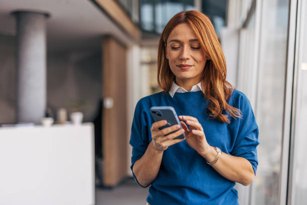 istock A confident businesswoman using smartphone while standing in office corridor 2187467320