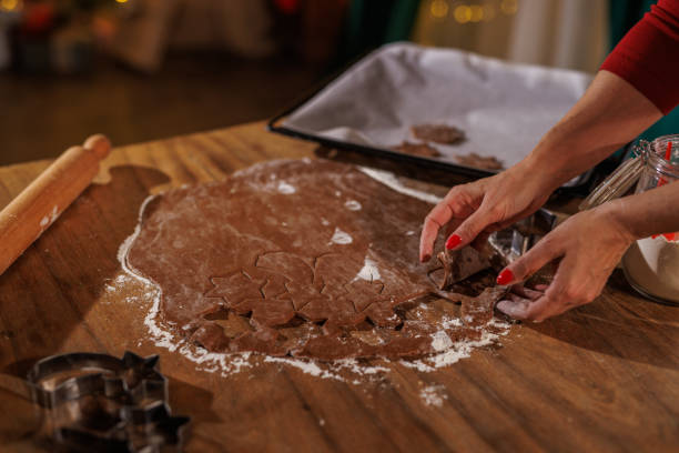 istock Hands crafting festive gingerbread cookies with cookie cutters in a warm kitchen 2187468550