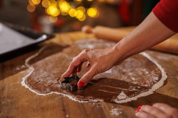 istock Hand using cookie cutter on dough with festive holiday lights glowing 2187468555