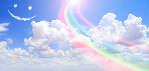istock Feeling happy and good mood concept. Horizontal nature banner with blue sky, pretty clouds, rainbow and funny cloud emoji. Rainbow Sky. Fluffy clouds with a giant arcing rainbow 2187469067
