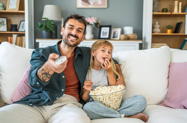 istock Dad and daughter watching tv at home 2187470347