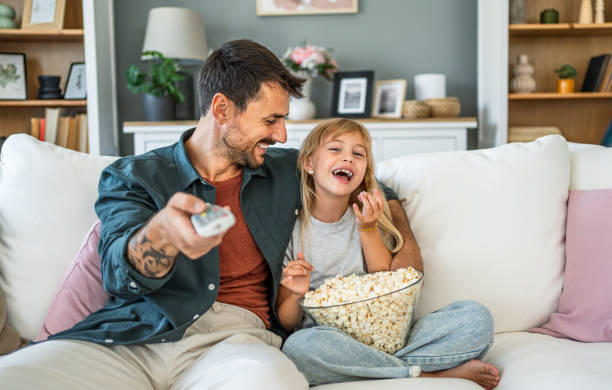 istock Dad and daughter watching tv at home 2187470536