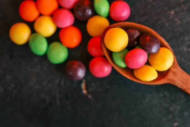 istock Colorful candy-coated chocolates in a wooden spoon on a dark textured surface. Bright, vibrant, and sweet treats with a fun and playful arrangement, perfect for dessert or snack concepts 2187470805