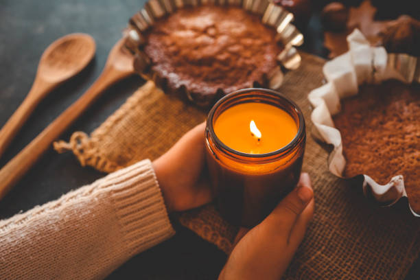 istock Burning candle in hands and pumpkin pie, cozy autumn 2187471954