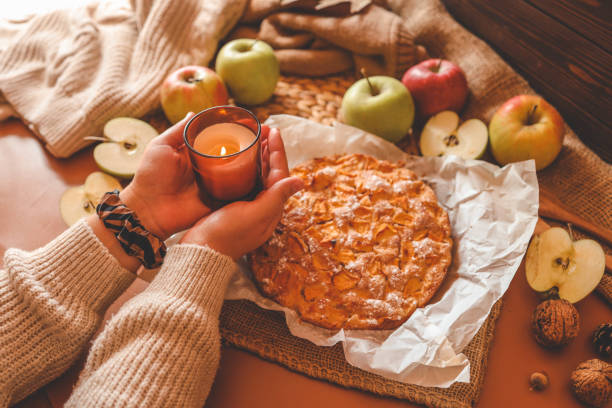 istock A cozy autumn setup featuring a freshly baked apple pie surrounded by apples, walnuts, a candle, and a warm drink 2187472116