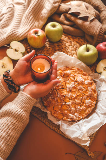istock A cozy autumn setup featuring a freshly baked apple pie surrounded by apples, walnuts, a candle, and a warm drink 2187472118