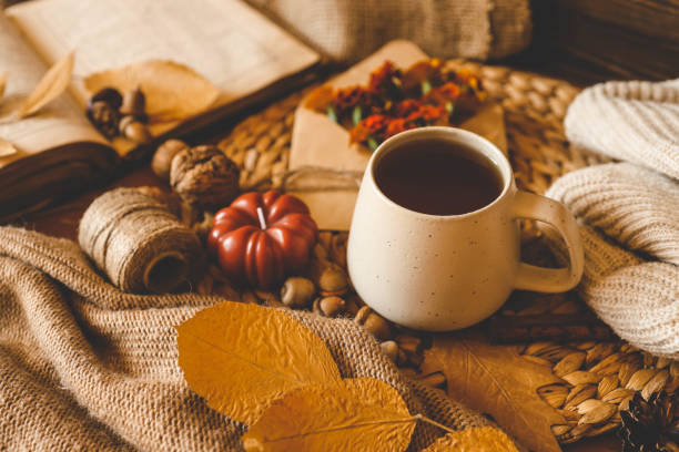 istock Cozy autumn composition with a ceramic mug of tea, surrounded by fall elements such as dried leaves, a pumpkin candle, marigold flowers, yarn, and a warm knitted sweater. Perfect for a relaxing fall atmosphere 2187472538