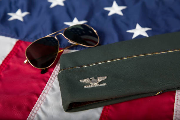 Army Officer’s uniform garrison cap with Colonel Insignia resting on American Flag.
