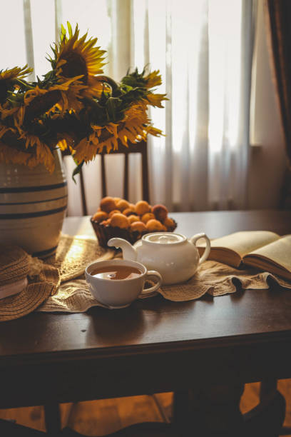 Cup of tea, open book and sunflowers in a vase, summer mood