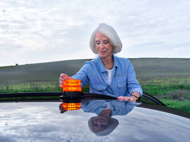 istock Elderly woman with her broken down car puts the emergency light on the roof 2187474352