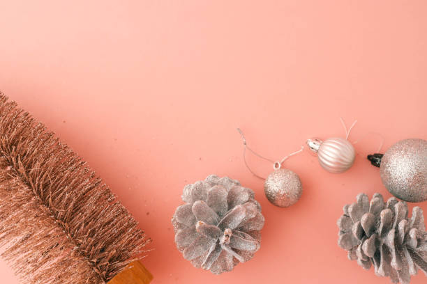 Minimalist flat lay composition of a metallic Christmas tree, silver pinecones, and glittery ornaments on a pastel pink background. Perfect for festive, seasonal, and holiday-themed designs