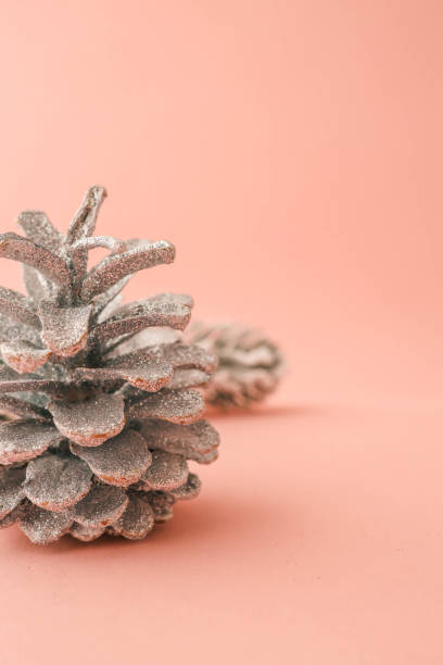 Minimalist flat lay composition of a metallic Christmas tree, silver pinecones, and glittery ornaments on a pastel pink background. Perfect for festive, seasonal, and holiday-themed designs