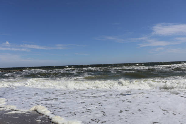 istock A bright and expansive ocean view featuring waves crashing onto the shore with foam and a clear blue sky above 2187478829