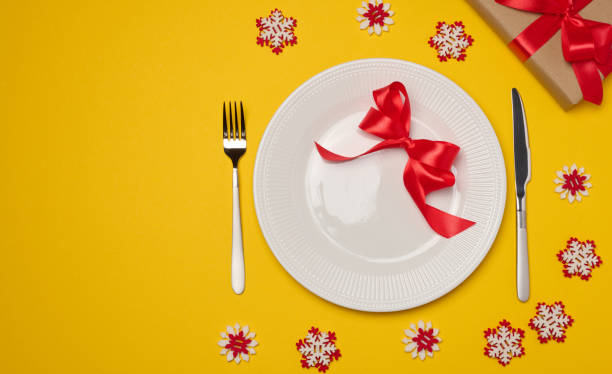 istock Empty white round plate, fork and knife on yellow background, top view 2187480586