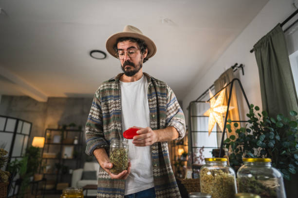 istock Adult man herbalist prepare tea with herbs from a jar at workshop 2187493336