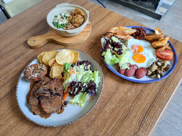 Chicken Meat Loaf With Potato, Cheese, BBQ Sauce And Vegetables. Germany Breakfast With Sunny Side Up Eggs, Roast Potato, Roast Tomato, Roast Mushroom, Red Beans, Lettuce, Mix Green Beef Frankfurter And Garlic Bread. Bubur Ayam Kaldu Or Chicken Porridge.