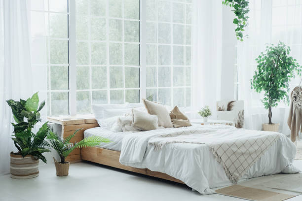 istock Cozy bedroom with large windows and greenery in a serene, sunlit space 2187502409
